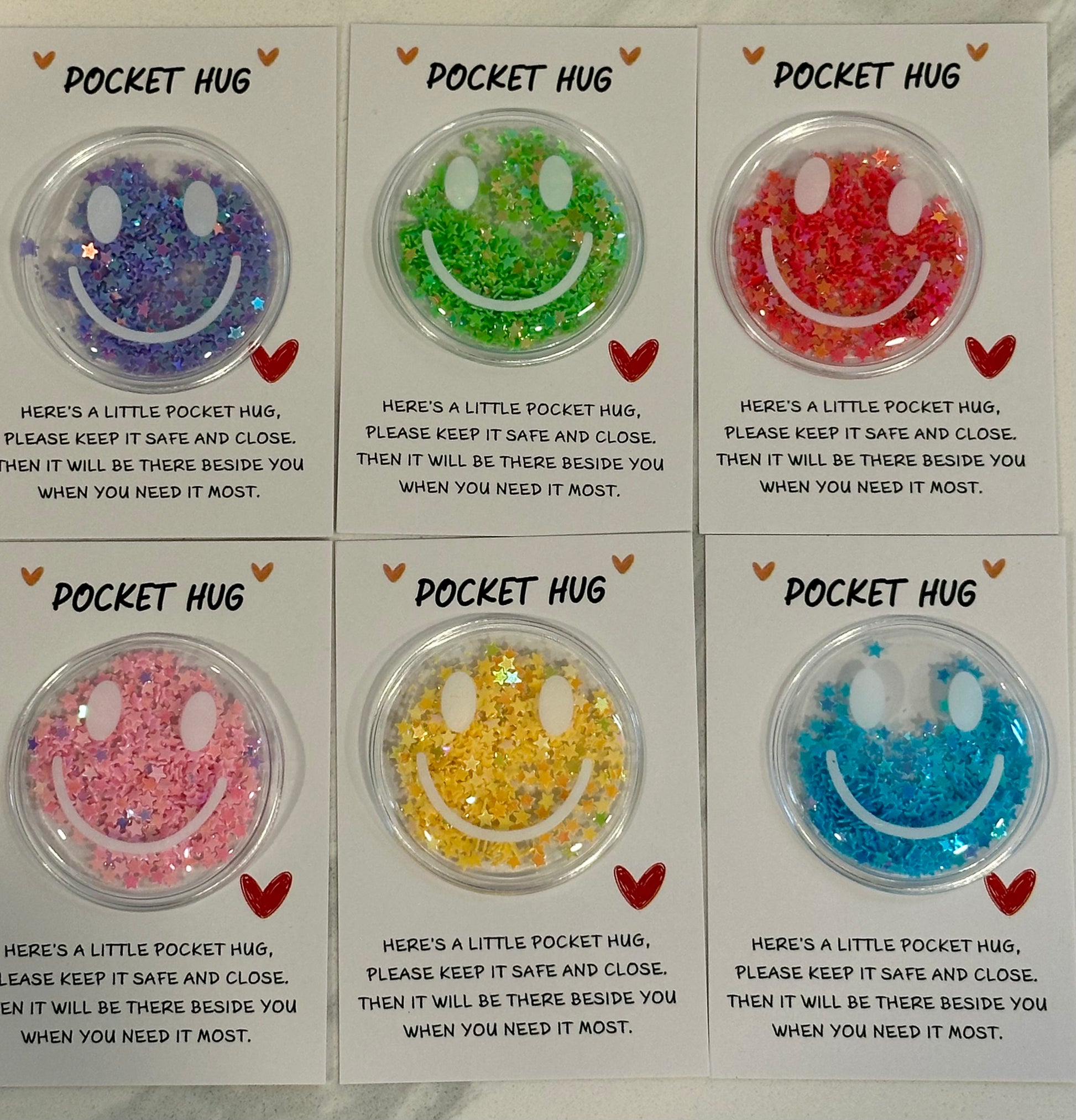 Glitter smiley Pocket Hug tokens on message cards in assorted colors