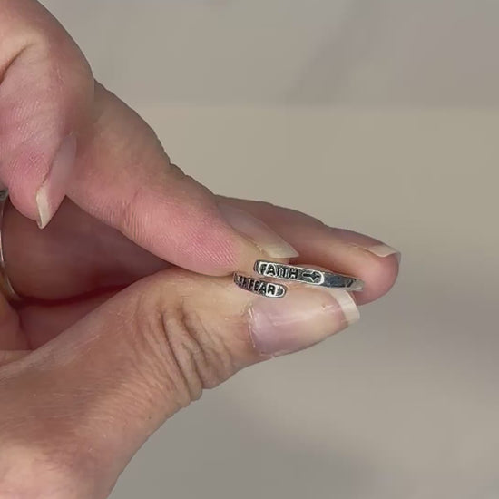 Adjustable silver wrap ring engraved with ‘Faith Over Fear'.