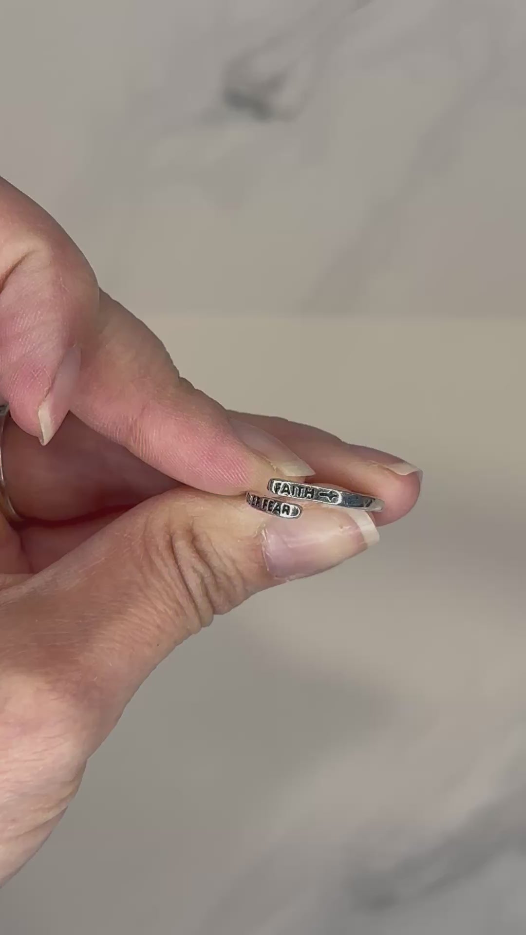 Adjustable silver wrap ring engraved with ‘Faith Over Fear'.